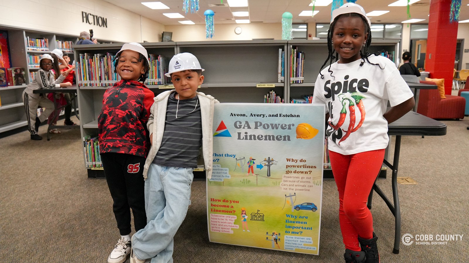 First-grade students at Clarkdale Elementary wearing hard hats and exploring a Georgia Power bucket truck