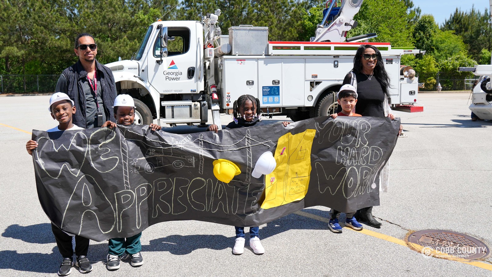 First-grade students at Clarkdale Elementary wearing hard hats and exploring a Georgia Power bucket truck
