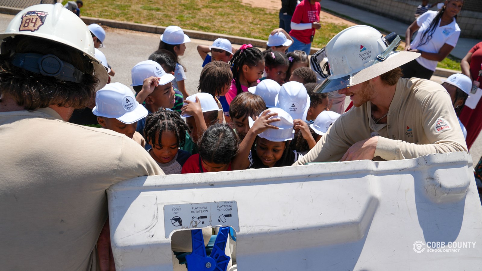 First-grade students at Clarkdale Elementary wearing hard hats and exploring a Georgia Power bucket truck