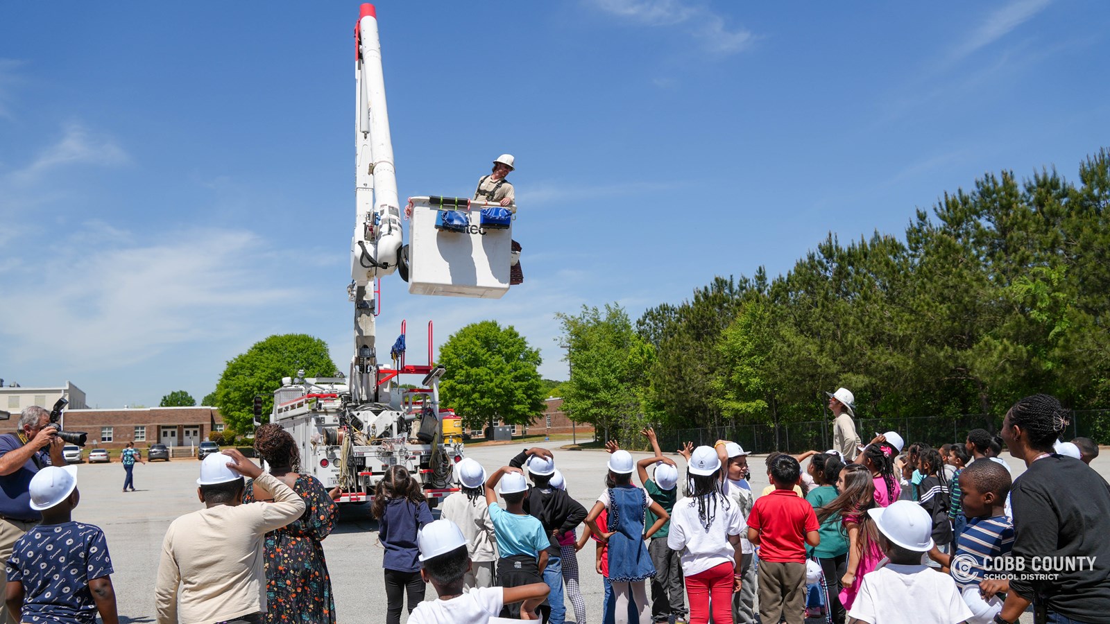 First-grade students at Clarkdale Elementary wearing hard hats and exploring a Georgia Power bucket truck