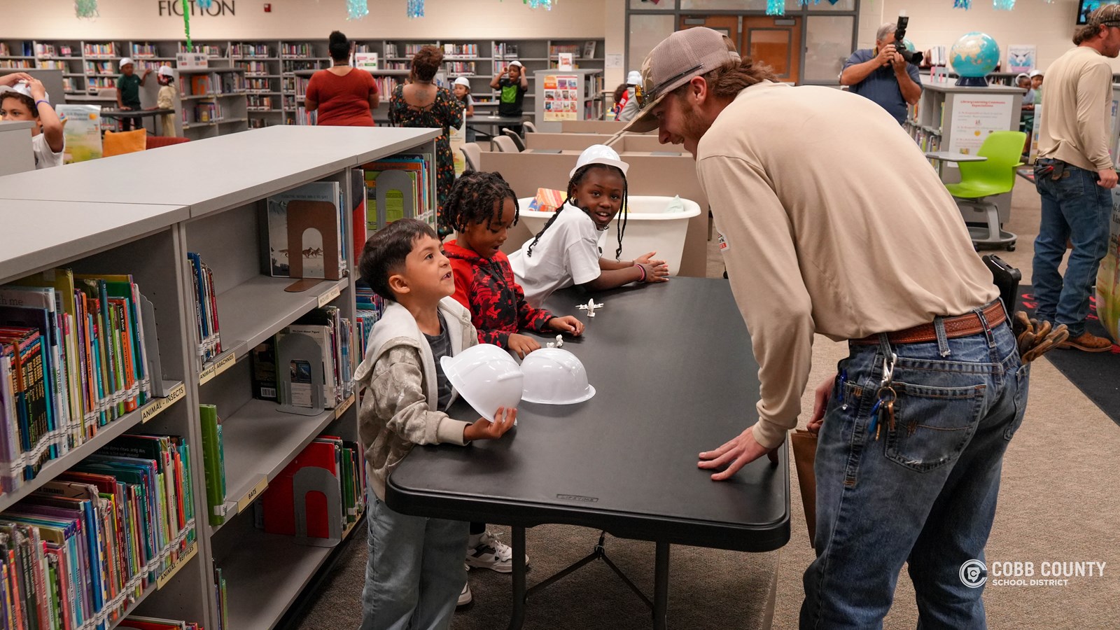 First-grade students at Clarkdale Elementary wearing hard hats and exploring a Georgia Power bucket truck