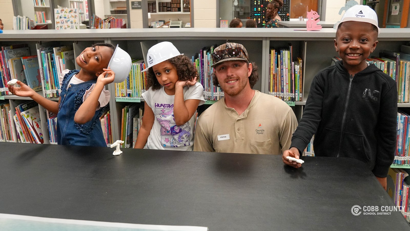 First-grade students at Clarkdale Elementary wearing hard hats and exploring a Georgia Power bucket truck