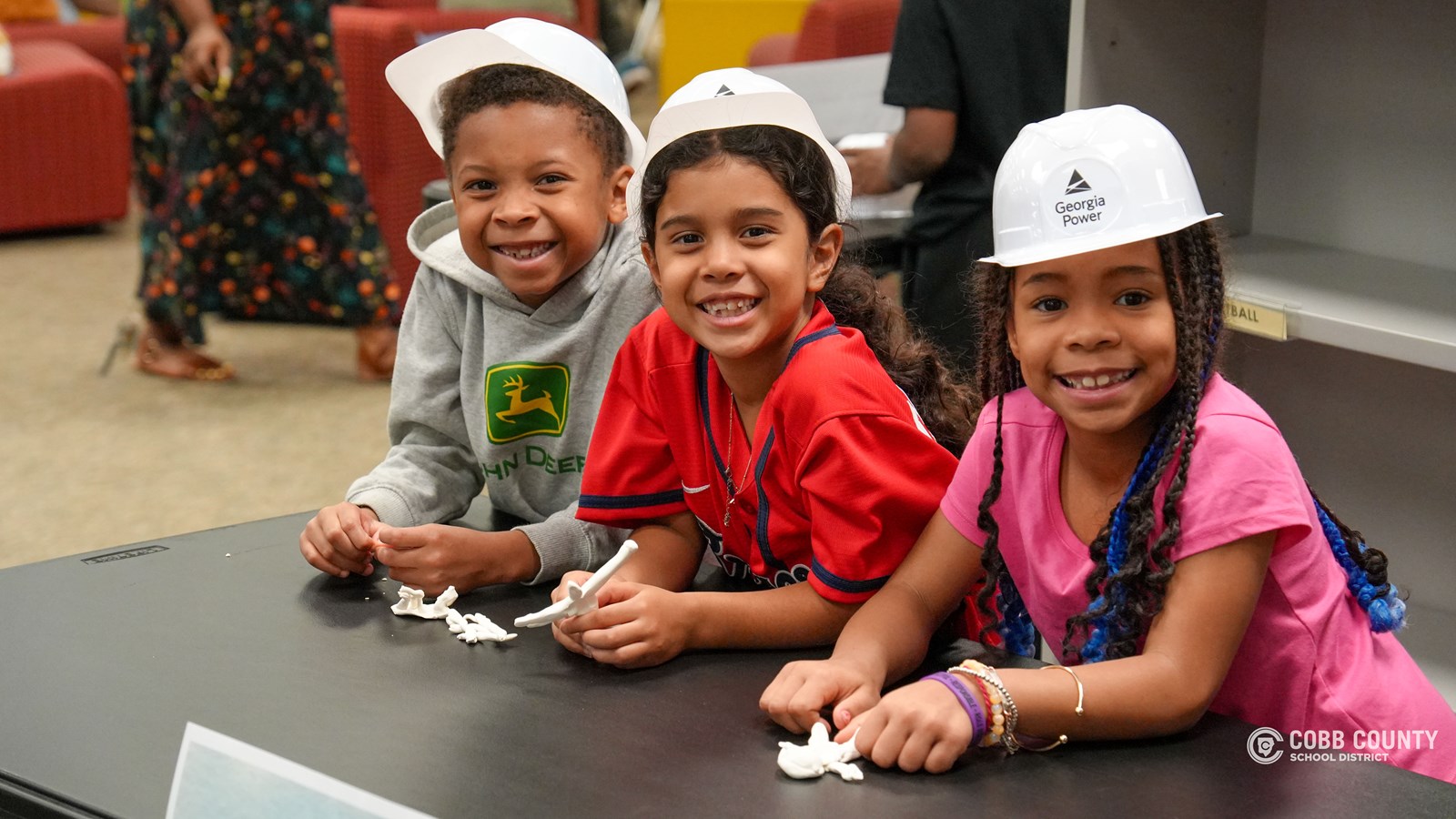 First-grade students at Clarkdale Elementary wearing hard hats and exploring a Georgia Power bucket truck