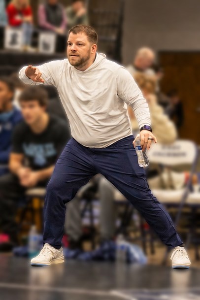 Coach Adams animated on the wrestling mat sidelines