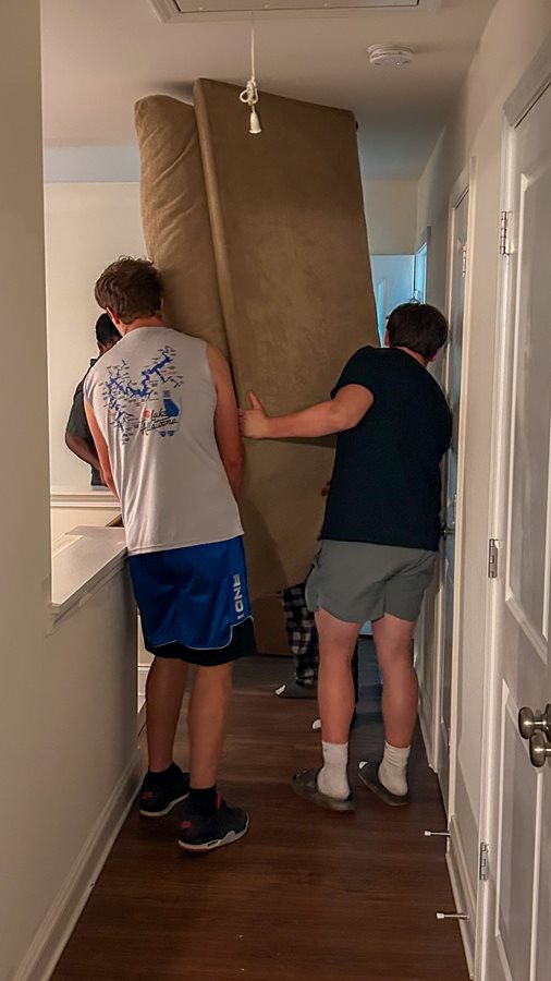 Harrison football players move a couch