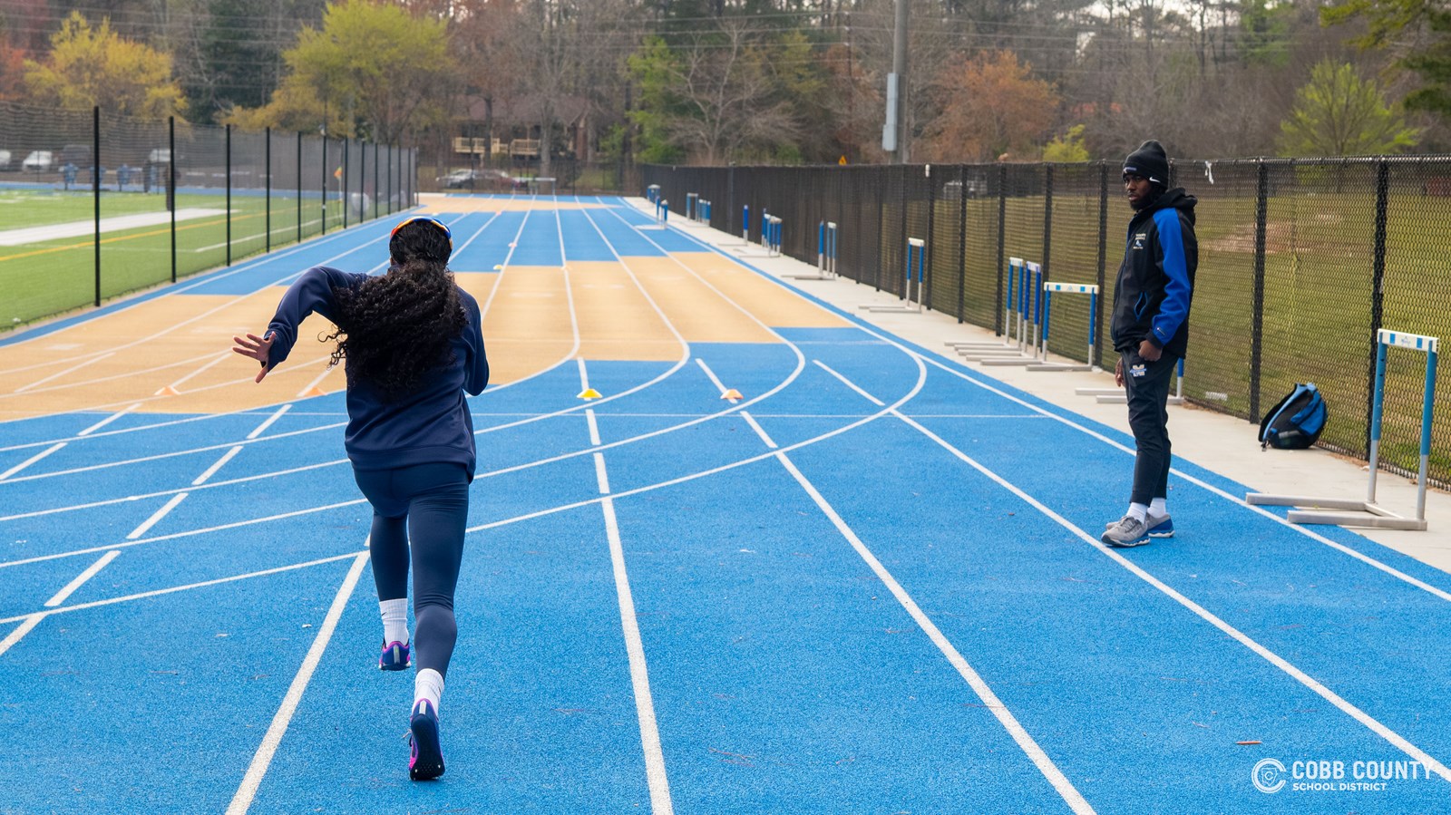 Coach Freeze watches closely as a McEachern sprinter works on her form