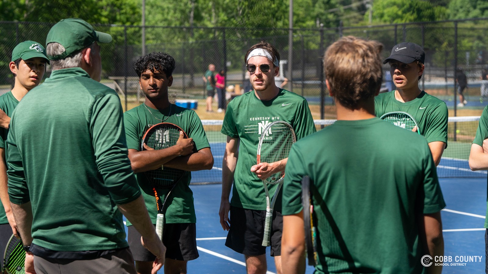 Nolen Jarl joins a KMHS tennis team huddle