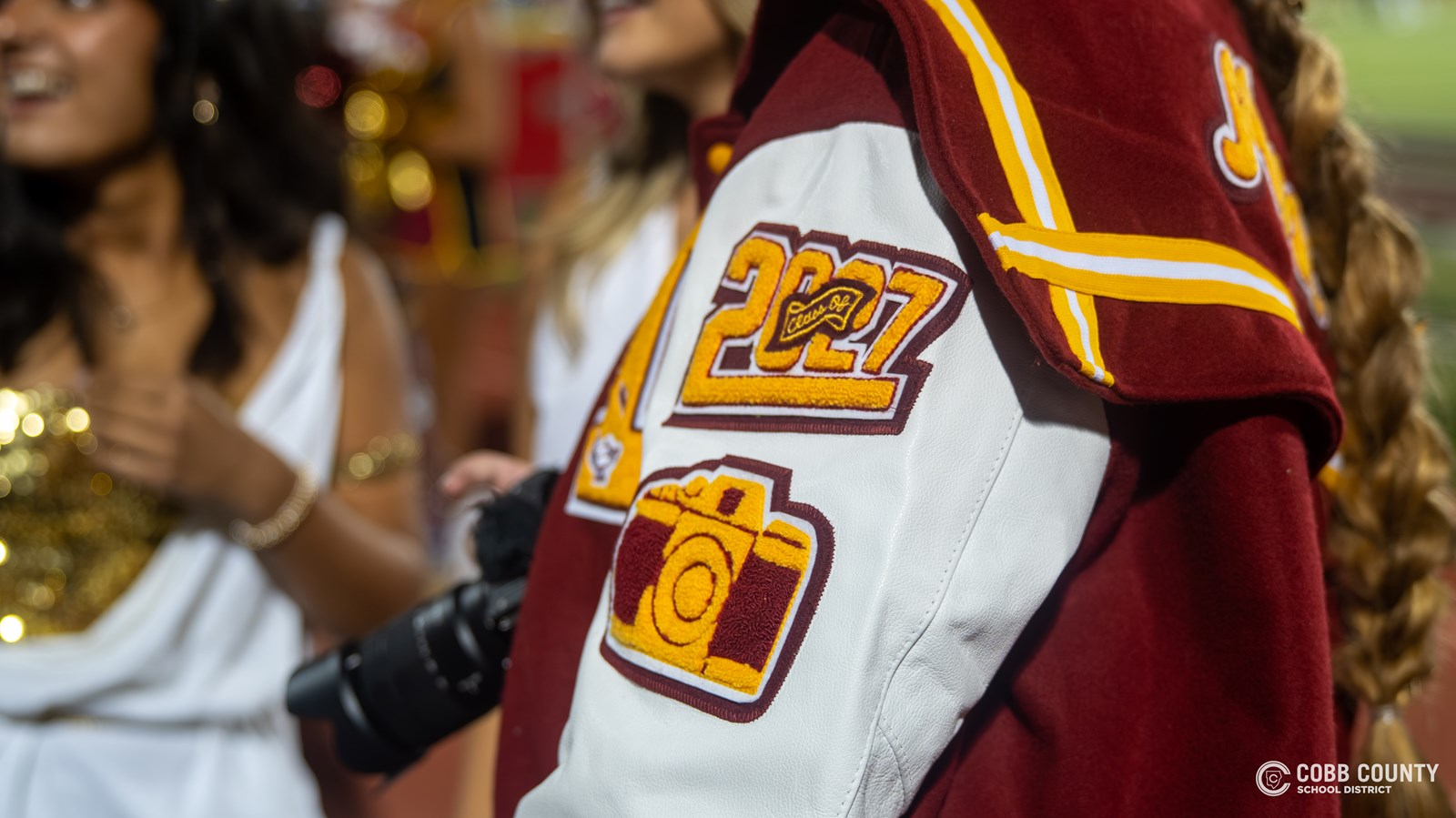 Even Audrey Moss' letterman's jacket features a camera