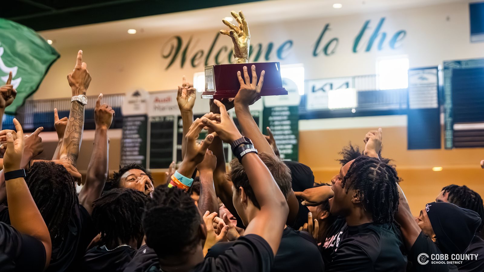The KMHS football team celebrates around the trophy