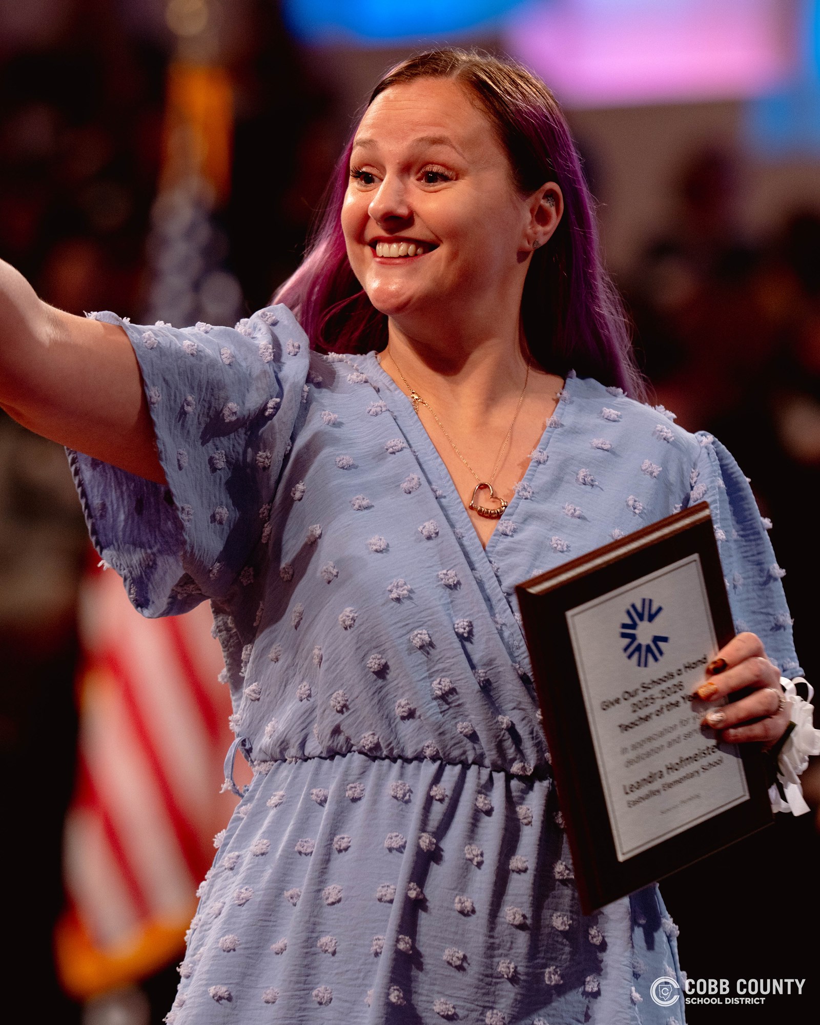 Teacher with plaque waving to students