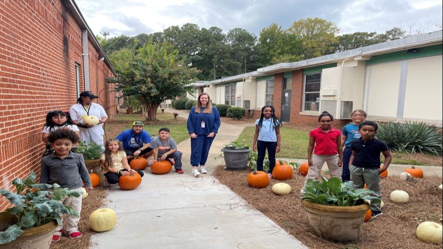 Picture of students from the garden club, along with pumpkins they have grown.