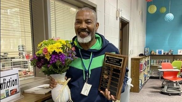 man holding flowers and plaque