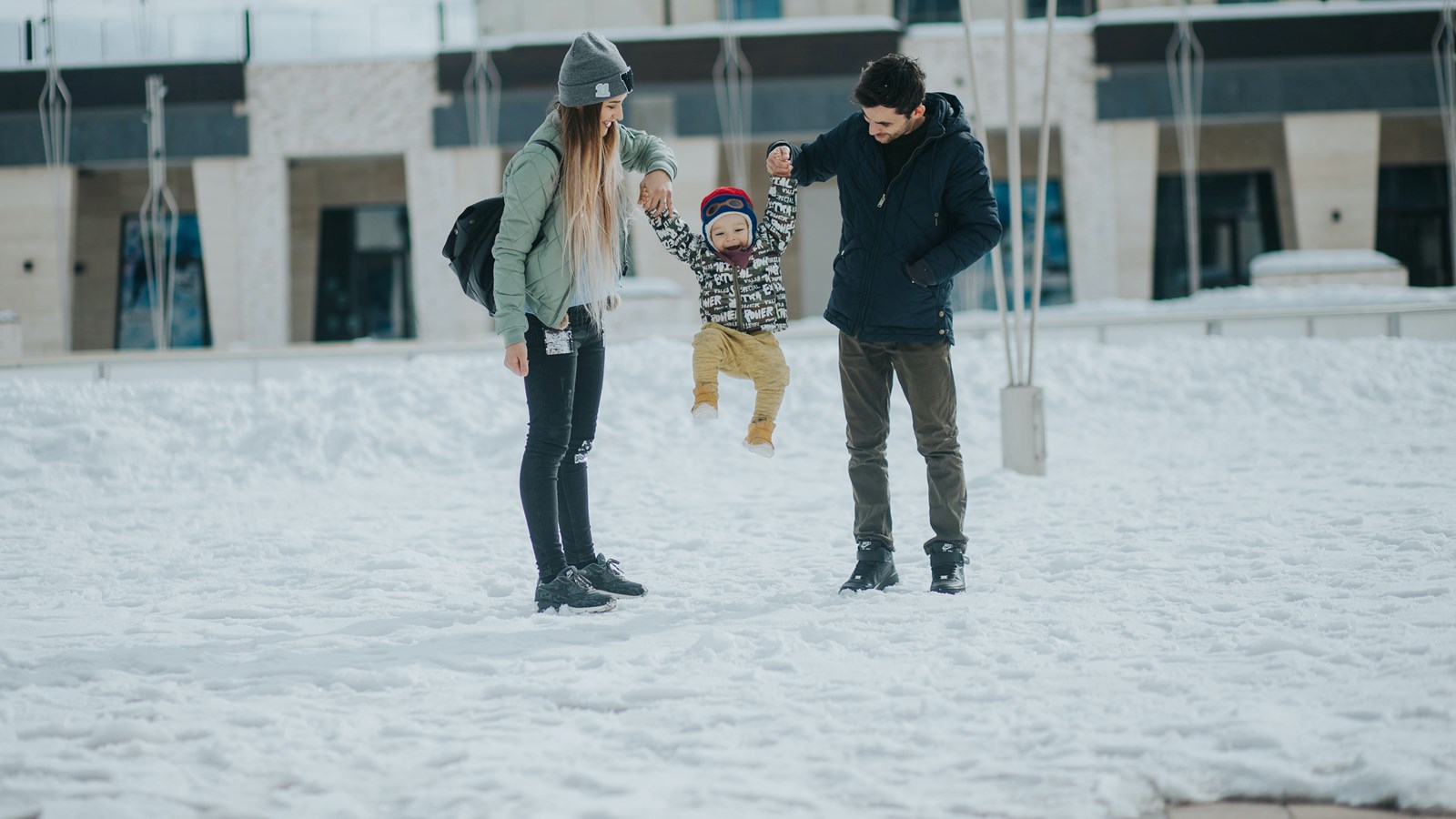 two adults and one child on a snow covered playground