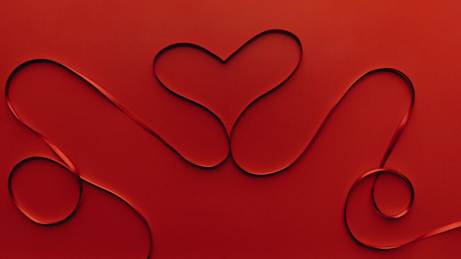 red ribbon heart on red background