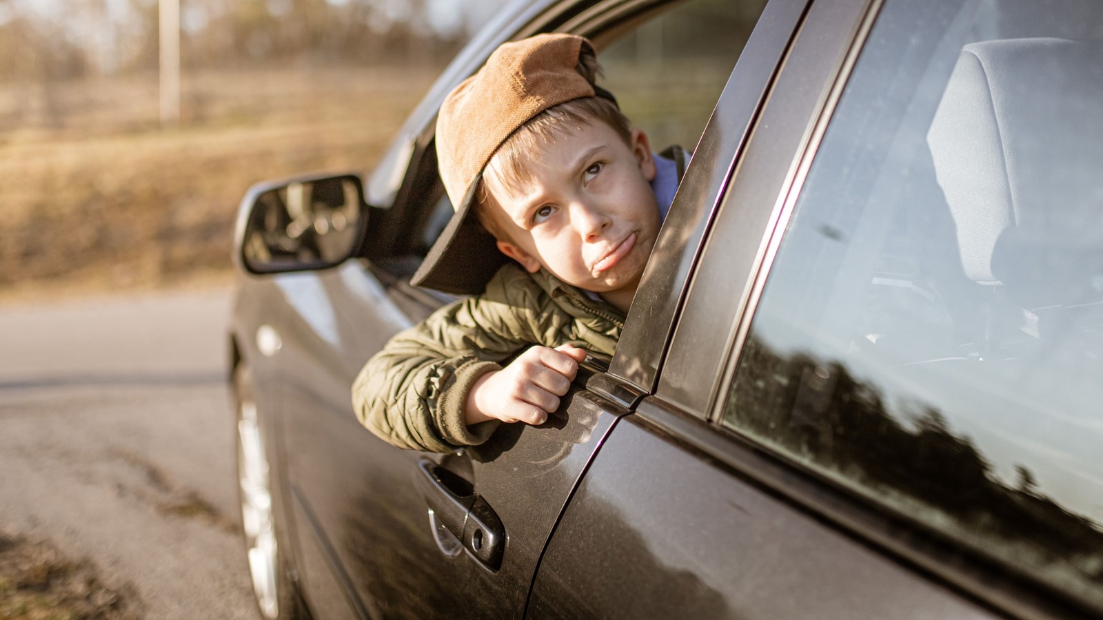 boy pouting while sitting in the driver's seat of a car