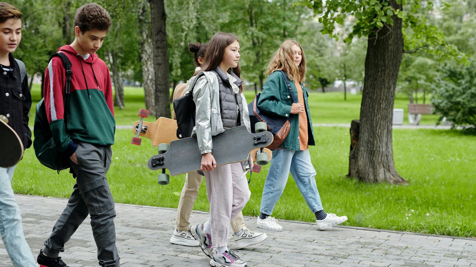 Elementary school students walking down a sidewalk in a park