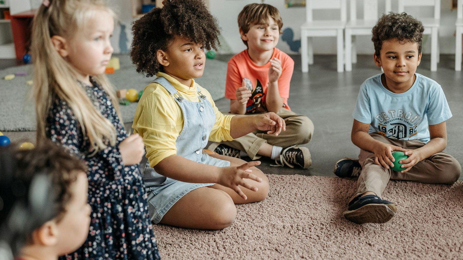 elementary school students sitting on a rug while playing a game