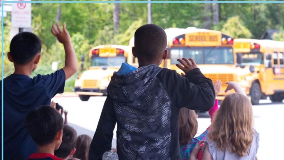 photo of children waving at a bus