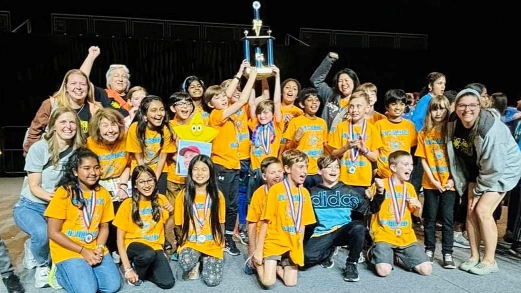 Members and coaches of Science Olympiad team celebrate with trophy.