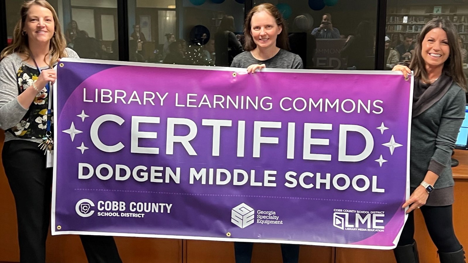 Dr. Alford, Ms. Bishop-Fink, and Ms. Cope hold the banner representing Dodgen's new status as a Library Learning Commons Certified School.